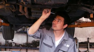 Otomobil tamircisinde çalışan bir adamın görüntüleri.