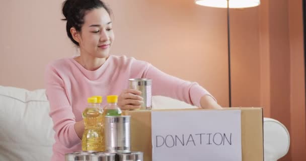 寄付箱付きの食べ物を持っているアジアの女性彼女の部屋で 寄付の考え方 — ストック動画
