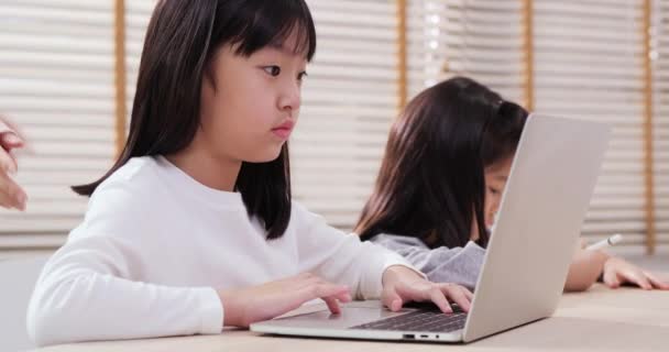 自宅でオンライン研究にラップトップを使用して女の子 母はオンラインで勉強するために娘の世話をする 家族とライフスタイルの概念 — ストック動画