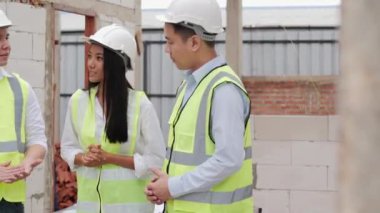 Erkekler ve kadınlar inşaat alanında çalışma sürecini tartışıyorlar.