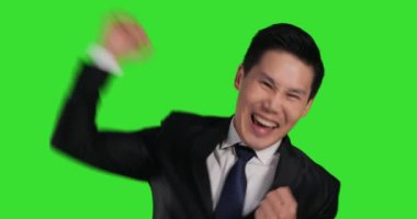 Asyalı takım elbiseli adam yeşil arka planda mutlu duygular gösteriyor.