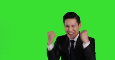 Asyalı takım elbiseli adam yeşil arka planda mutlu duygular gösteriyor.