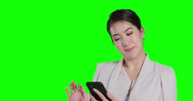 Asyalı kadın yeşil arka planda akıllı telefon kullanıyor.