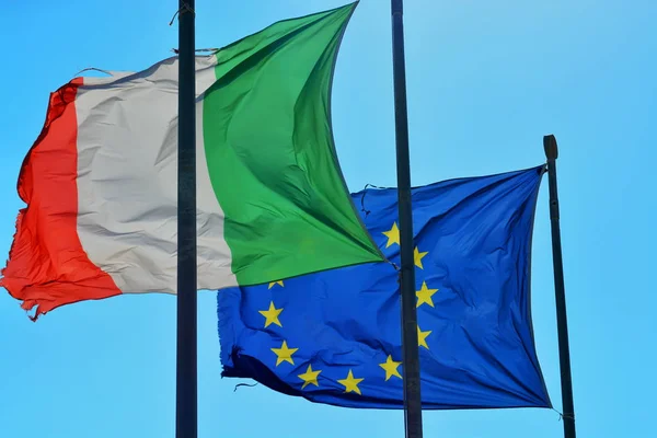 Worn waving flags of Italy and Europe.