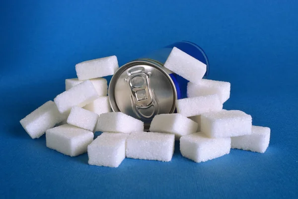 Una lata de bebida azucarada rodeada de terrones de azúcar blanco . —  Fotos de Stock