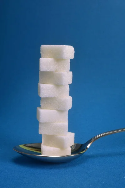 Une cuillère contenant une pile de cubes de sucre blanc . — Photo