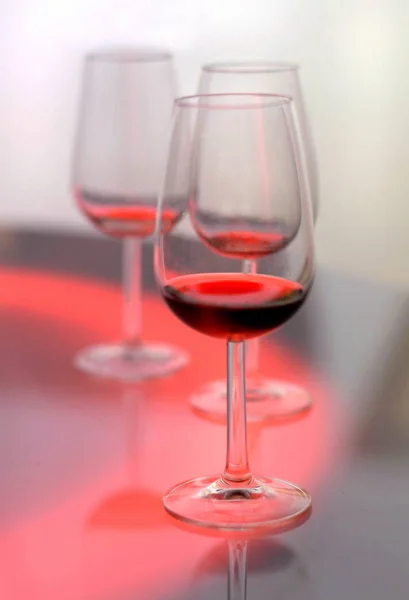 Três copos de vinho tinto em fundo de cor brilhante — Fotografia de Stock