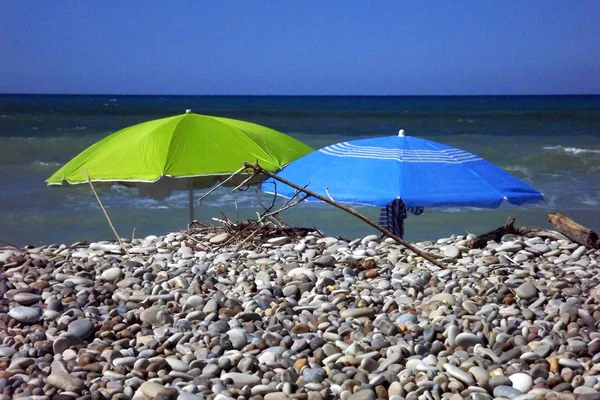 Yaban çakıl plajında şemsiyeler. — Stok fotoğraf