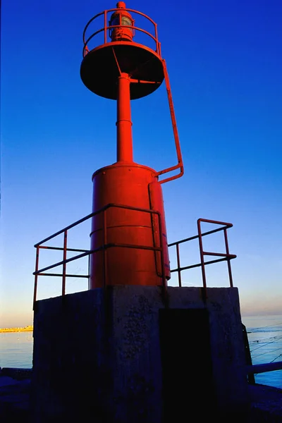 Mała czerwona latarnia morska przy wejściu do portu śródziemnomorskich południowych Włoch. — Zdjęcie stockowe
