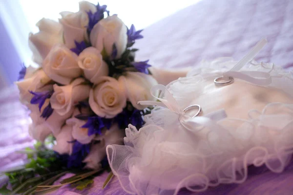 Close up van trouwringen van de pasgetrouwden met het boeket van de bloemen op de achtergrond. — Stockfoto