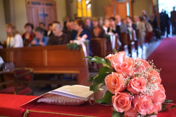 O buquê de noiva e os convidados aguardam a entrada da noiva e do noivo em uma igreja — Fotografia de Stock