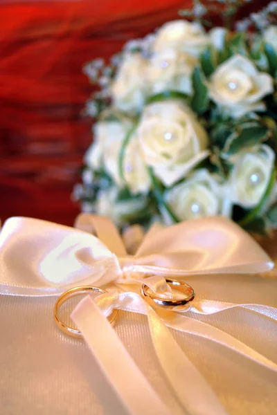 Close up de alianças de casamento dos recém-casados com o buquê de flores no fundo — Fotografia de Stock