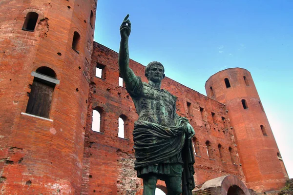 Turin, Piedmont, Italy the Archaelogical Park of Romans ruins and statue of Caesar Augustus with Torri Palatine in background. — Stock Photo, Image