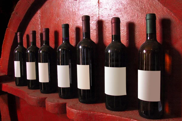 Turin, piemont / italien. -24 / 10 / 2009 - die "Weinmesse". sieben Flaschen Wein mit eigenem Schatten auf einem hölzernen — Stockfoto