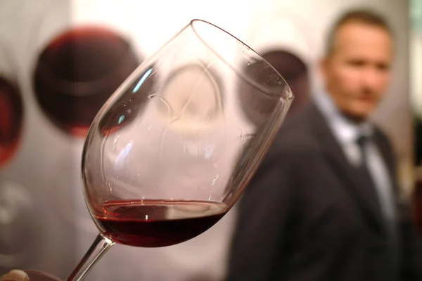 Turin, Piedmont/Italy -10/24/2009- Tasting a glass of red wine with a standing man in background — Stock Photo, Image