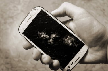 Bozuk ekranlı bir akıllı telefonu tutan erkek el.