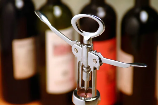 Steel corkscrew with bottles of wine in the background