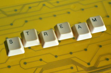 Klavye tuşları arka planda sarı elektrik devresinde Akış sözcüğünün biçimini oluşturur.