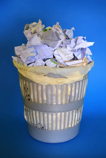 Uma cesta cheia de papel sobre fundo azul . — Fotografia de Stock