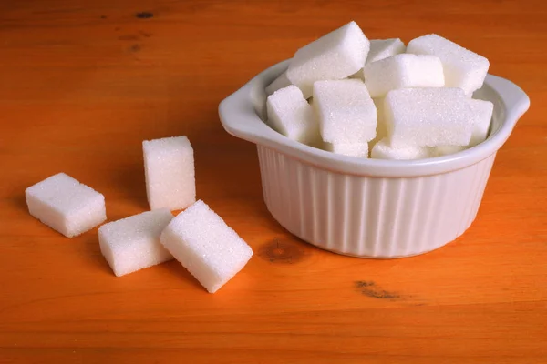 Bol plein de cubes de sucre sur table en bois . — Photo