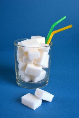 Cam beyaz şeker küpleri ve iki içme pipetleri dolu.