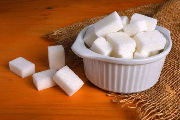 Skål full av sockerbitar på träbord. — Stockfoto