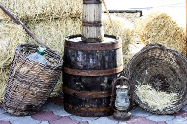 Kırsal natürmort. İki hasır sepet saman ve boş bir şarap şişesi ile büyük bir eski namlulu. Eski gaz lambası .