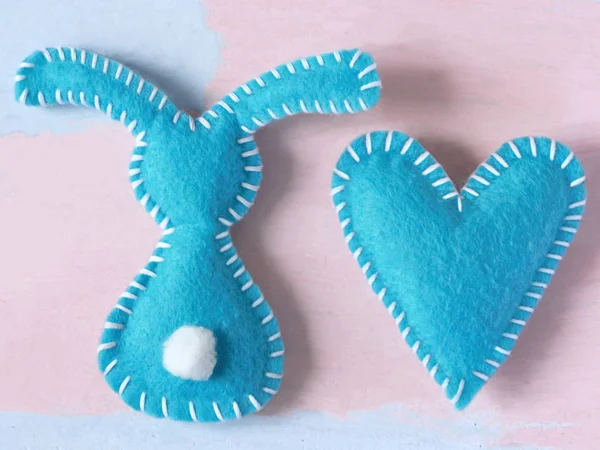 Hellblauer Hase und Herz auf blassrosa Hintergrund. Valentinstag oder frohe Ostern Hintergrund für Grußkarte Vorlage. Handarbeit aus Filz. . — Stockfoto