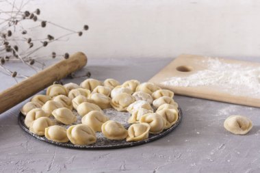Un ve oklava ile masada yuvarlak bir tabakta ev yapımı ravioli