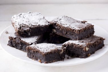 Beyaz bir tabaktabaktabaktabaklezzetli çikolatalı kek, pudra şekeri ile toz. Ev yapımı pişirme. Geleneksel Amerikan Pastası.