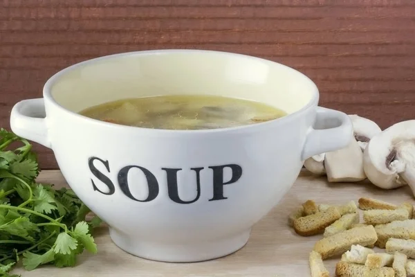 Schaal van kippenbouillon met champignons paddestoelen close-up op een lichte houten achtergrond — Stockfoto