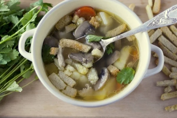 Kom kippenbouillon met champignons champignons in een lepel close-up op grijze achtergrond — Stockfoto