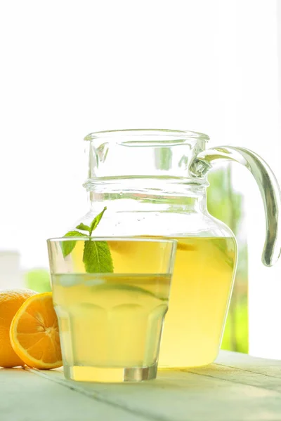 Jug and glass with lemonade on wooden table. — Stock Photo, Image