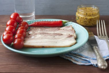 Pişmiş domuz göbek veya pastırma domates ile bir plaka ince dilimleri içine dilimlenmiş, hardal ile döktü.