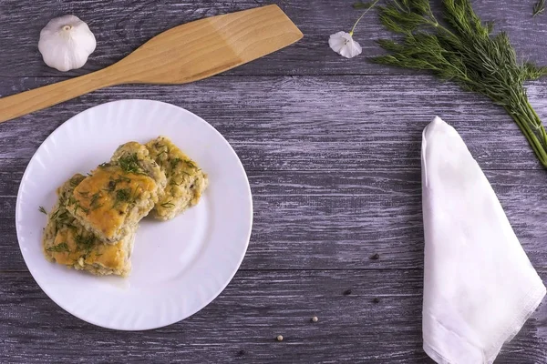 Delicious homemade casserole of zucchini, rice and cheese on a white plate on a wooden background.