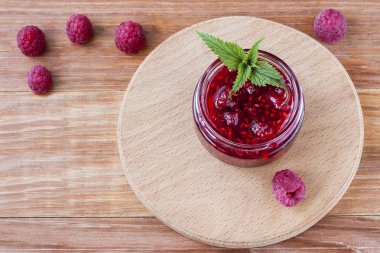 Ahşap arka plan üzerinde taze ahududu ve nane yakın çekim ile ahududu reçeli ile Cam küçük tabak. Kopyalama alanı