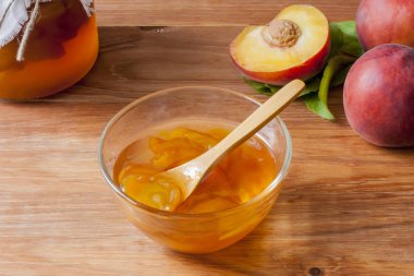 Piala sabah güneşinde masanın üzerinde ahşap yuvarlak standı üzerinde ev yapımı şeftali reçeli bir kaşık ile. Ev yapımı koruma kavramı. Yakın çekim