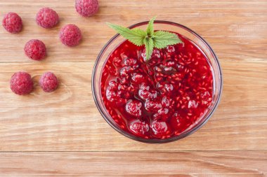 Ahşap arka plan üzerinde taze ahududu ve nane yakın çekim ile ahududu reçeli ile Cam küçük tabak.