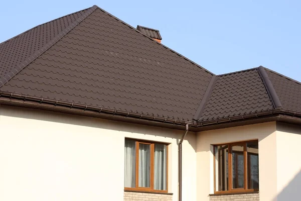 푸른 하늘을 배경으로 창문이있는 집의 갈색 타일 지붕 — 스톡 사진