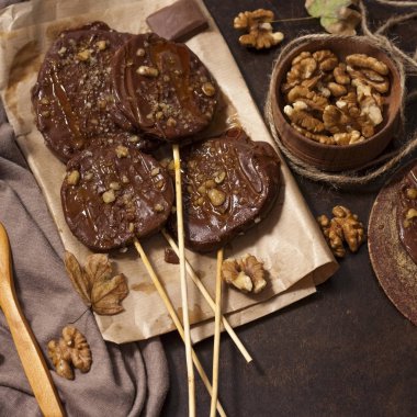 Koyu bir arka plan üzerinde şişler üzerinde çikolata, karamel sır ve ceviz elma dilimleri