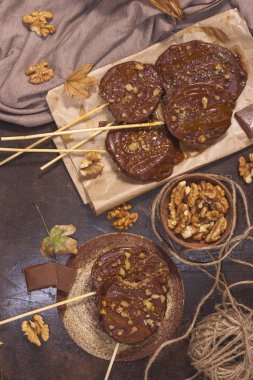 Koyu bir arka plan üzerinde şişler üzerinde çikolata, karamel sır ve ceviz elma dilimleri