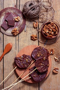 Koyu bir arka plan üzerinde şişler üzerinde çikolata, karamel sır ve ceviz elma dilimleri