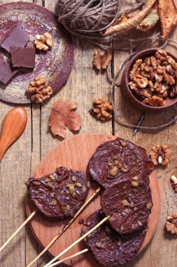 Ahşap bir arka plan üzerinde şişler üzerinde çikolata, karamel sır ve ceviz elma dilimleri