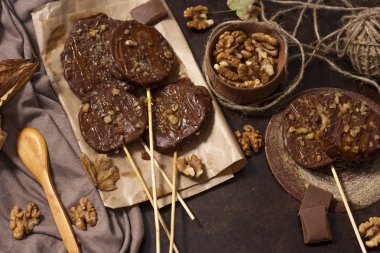 Koyu bir arka plan üzerinde şişler üzerinde çikolata, karamel sır ve ceviz elma dilimleri