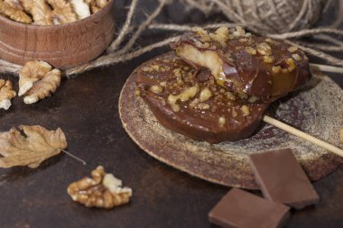 Koyu bir arka plan üzerinde şişler üzerinde çikolata, karamel sır ve ceviz elma dilimleri