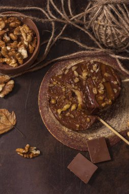 Koyu bir arka plan üzerinde şişler üzerinde çikolata, karamel sır ve ceviz elma dilimleri