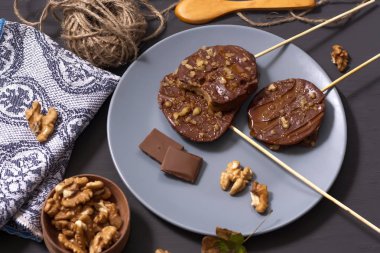 Koyu bir arka plan üzerinde şişler üzerinde çikolata, karamel sır ve ceviz elma dilimleri