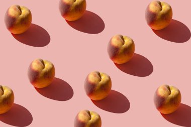 Pastel pembe arka plan üzerinde birçok sulu olgun şeftali bir desen. Yaratıcı düzen