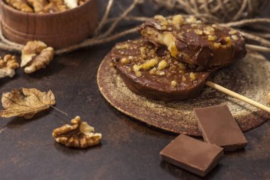 Koyu bir arka plan üzerinde şişler üzerinde çikolata, karamel sır ve ceviz elma dilimleri