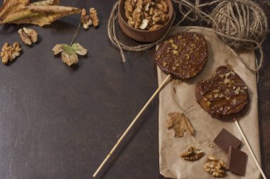 Koyu bir arka plan üzerinde şişler üzerinde çikolata, karamel sır ve ceviz elma dilimleri